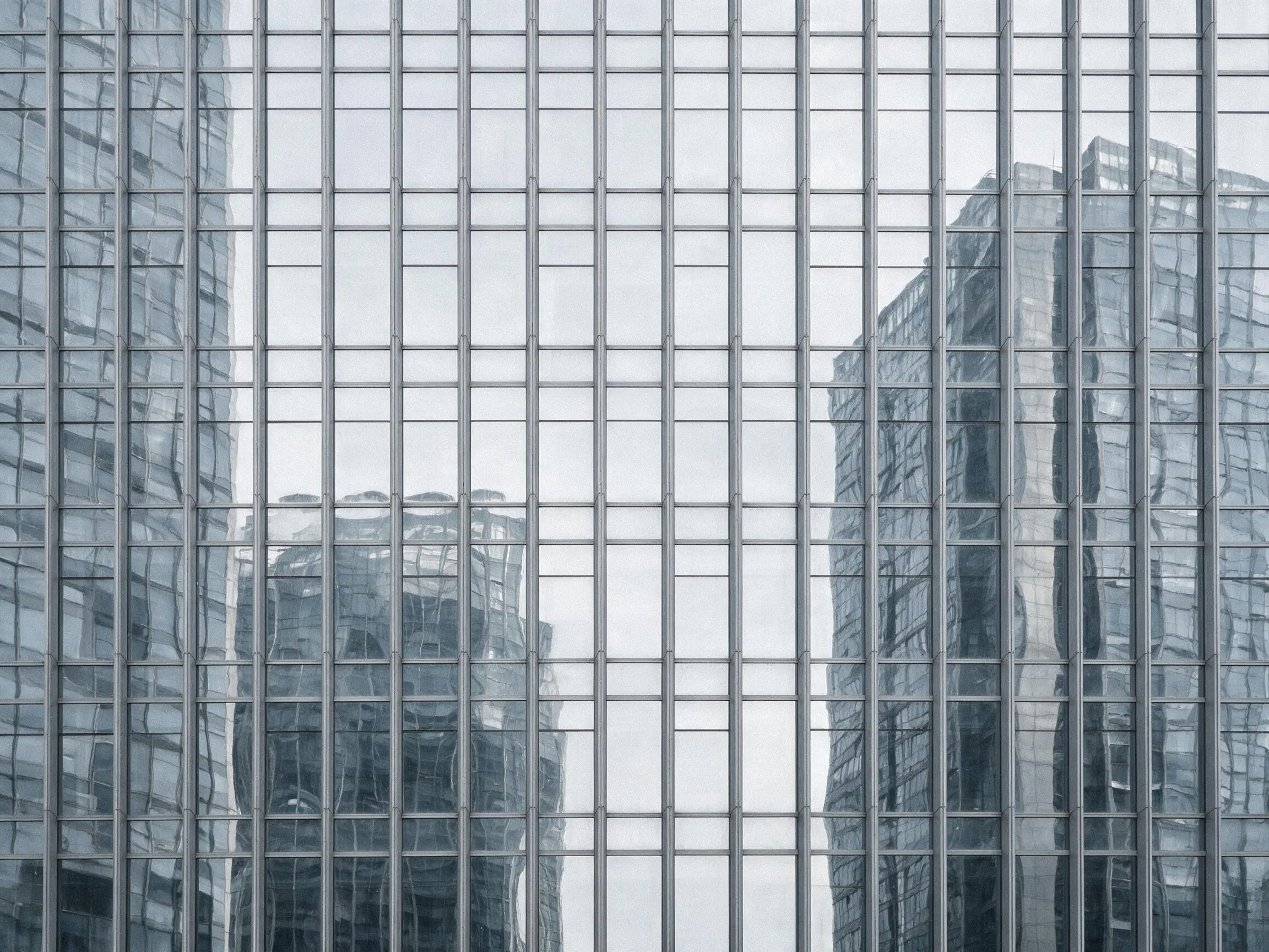 A repeating grid of glass and steel curtain walling, reflecting neighbouring towers.